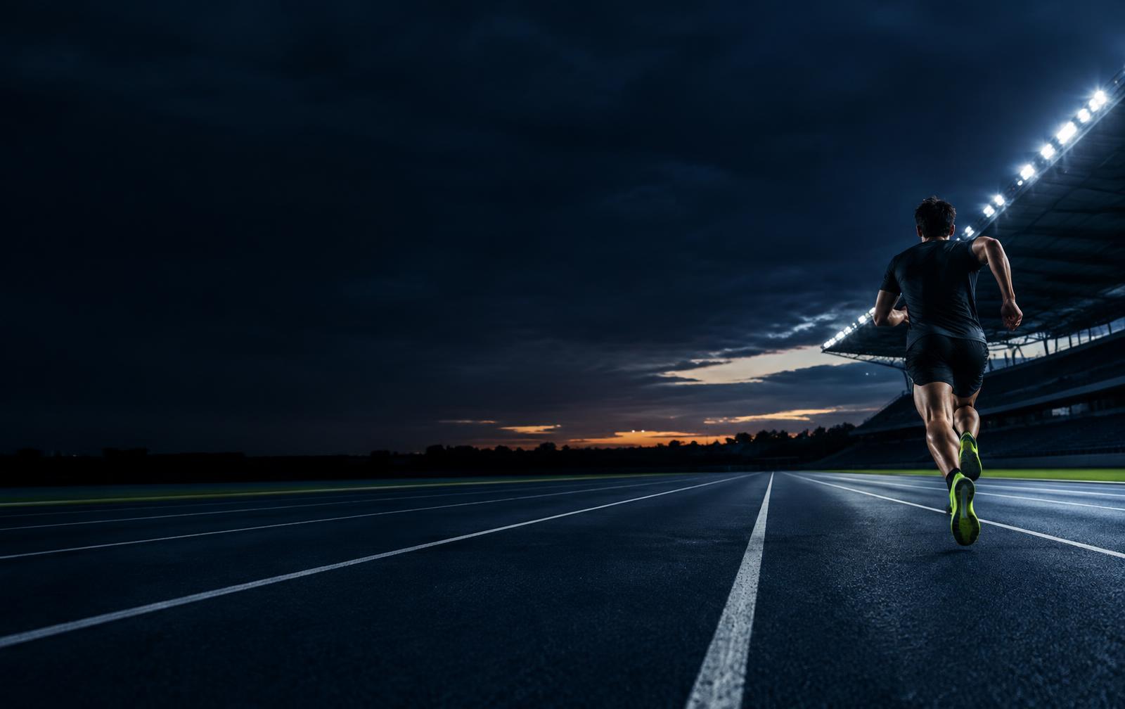 Corredor en una pista de atletismo al anochecer